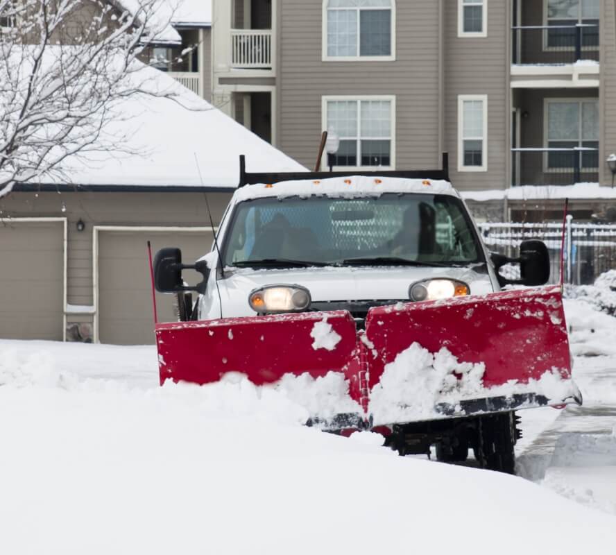 a truck plowing snow in a parking lot